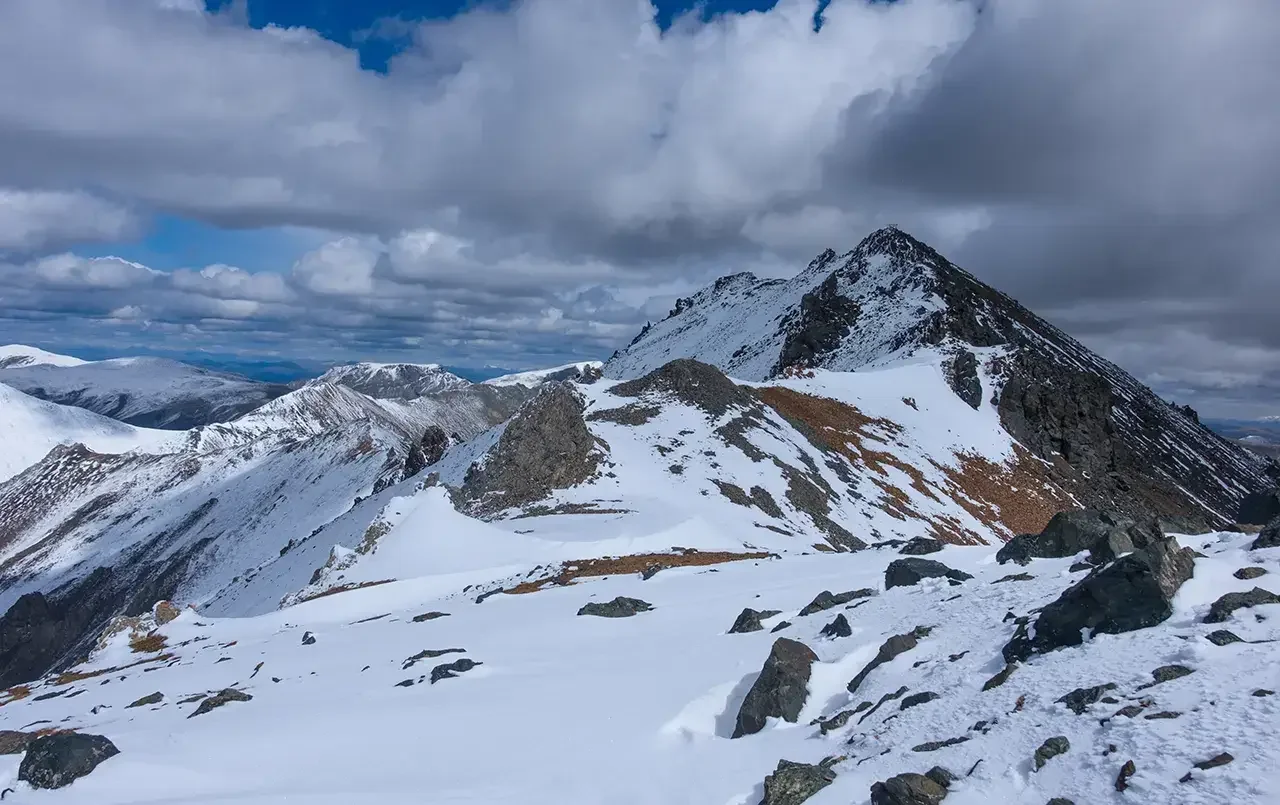 Снежные горные Курайского хребта под плотными облаками.